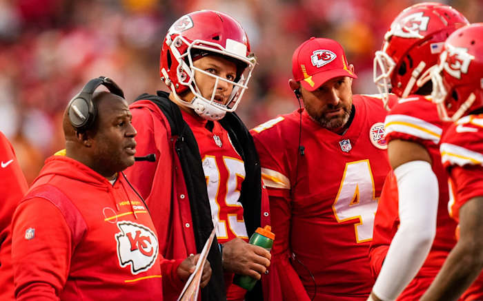 Jan 30, 2022; Kansas City, Missouri, USA; Kansas City Chiefs quarterback Patrick Mahomes (15) huddles with offensive coordinator Eric Bieniemy and quarterback Chad Henne (4) during a timeout in the second half of the AFC Championship game against the Cincinnati Bengals at GEHA Field at Arrowhead Stadium. Mandatory Credit: Jay Biggerstaff-USA TODAY Sports